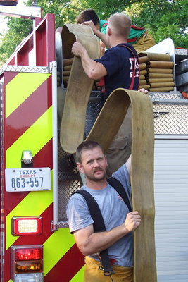 Image: Daniel Ballard helps load the hose back onto the fire truck.