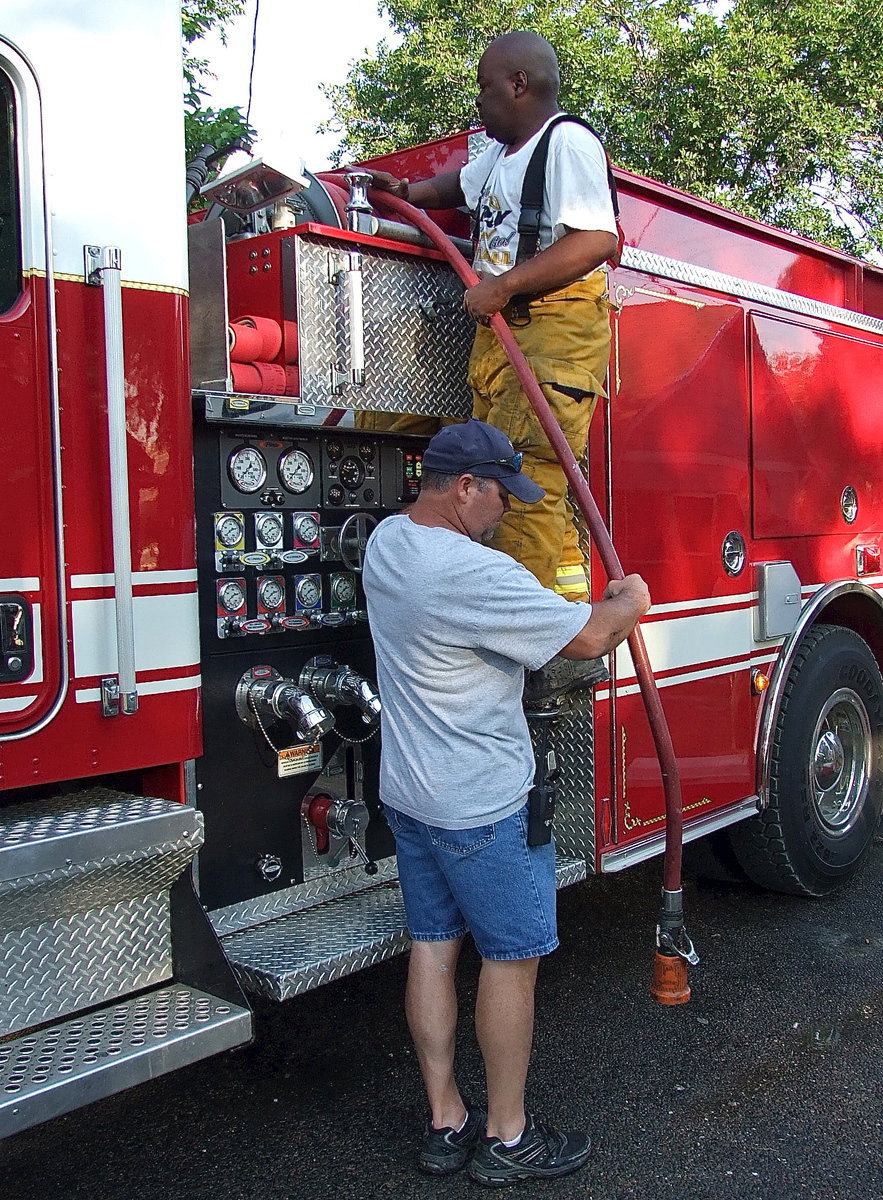 Image: Italy firefighters, Jackie Cate, and, Lynn Lambert, reel in the hose.