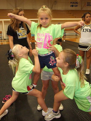 Image: Just like the big girls! Ariana Walker, Charlea Padilla and Kiara Bueno, with help from a spotter, elevate their cheer game.