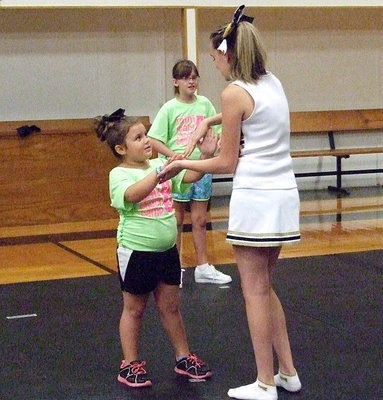 Image: Cheerleader Kirby Nelson demonstrates technique to camper Tinzley Enriquez.