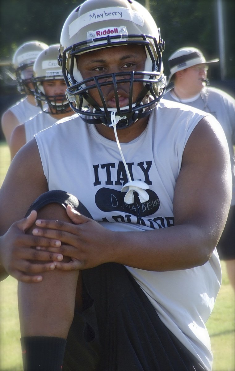 Image: Gladiator senior Darol Mayberry and his teammates get stretched before starting a 2-a-day workout.