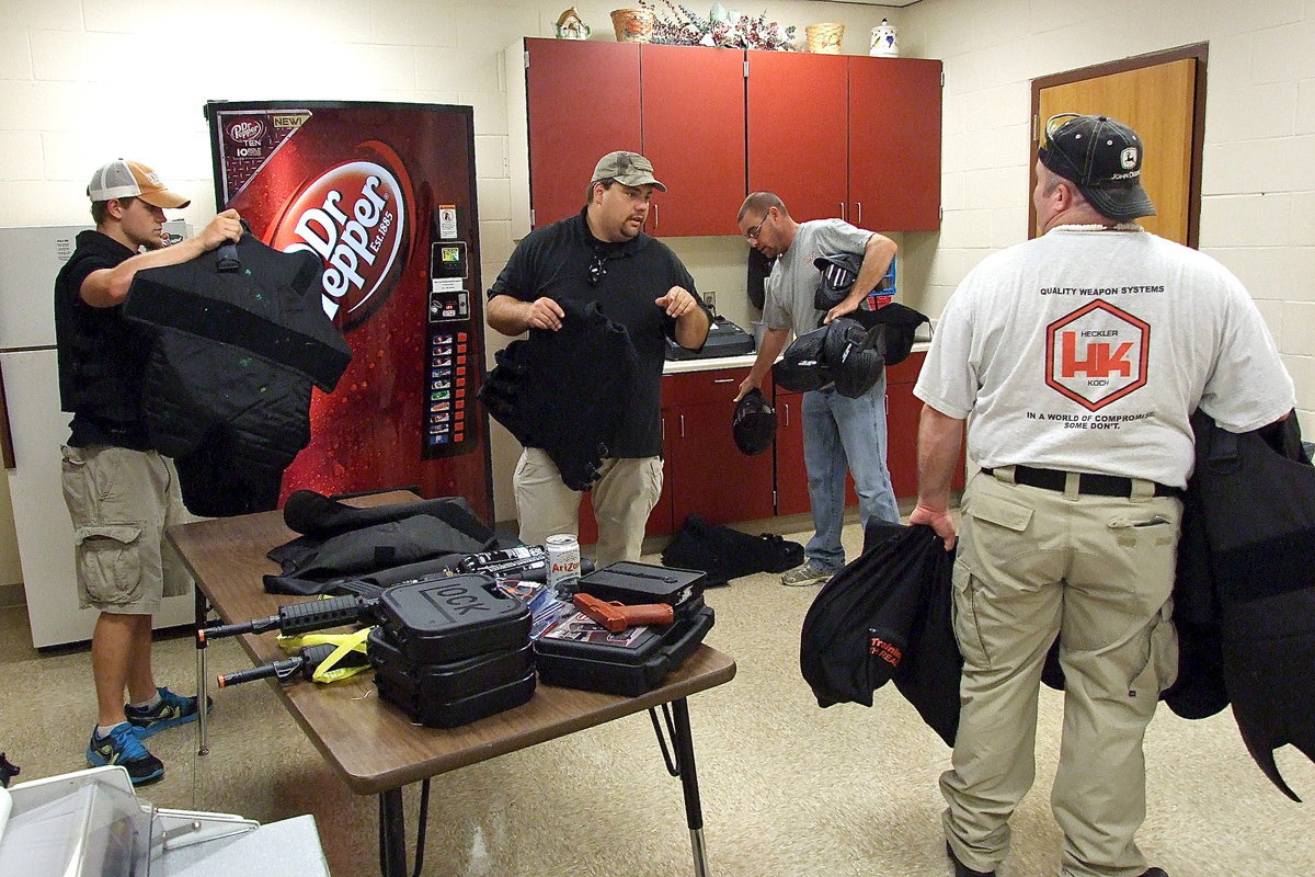 Image: Italy Police Officer Eric Tolliver receives help gathering protective equipment and modified paintball guns to be used in the training scenarios.