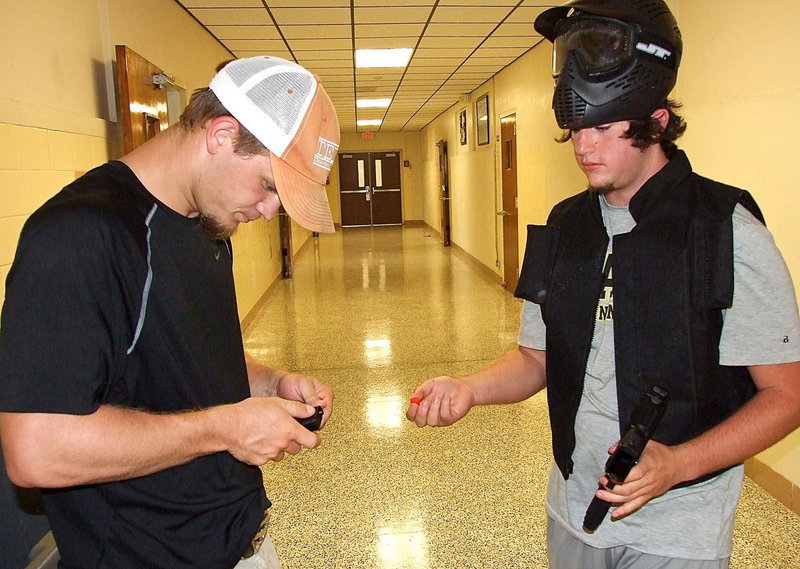 Image: Italy HS alumni volunteer Chase Hamilton helps Kyle Fortenberry load his modified handgun with custom velcro bullets designed to stick to the protective vests.