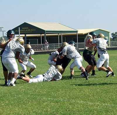 Image: Bailey Walton(99) grabs a foot while Levi McBride(3) and Coby Bland(44) tag an Eagle runner.
