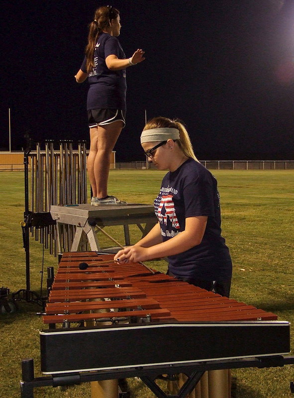 Image: Drum Major Alexis Sampley directs her troops from atop the podium while Reagan Adams plays the marimba.