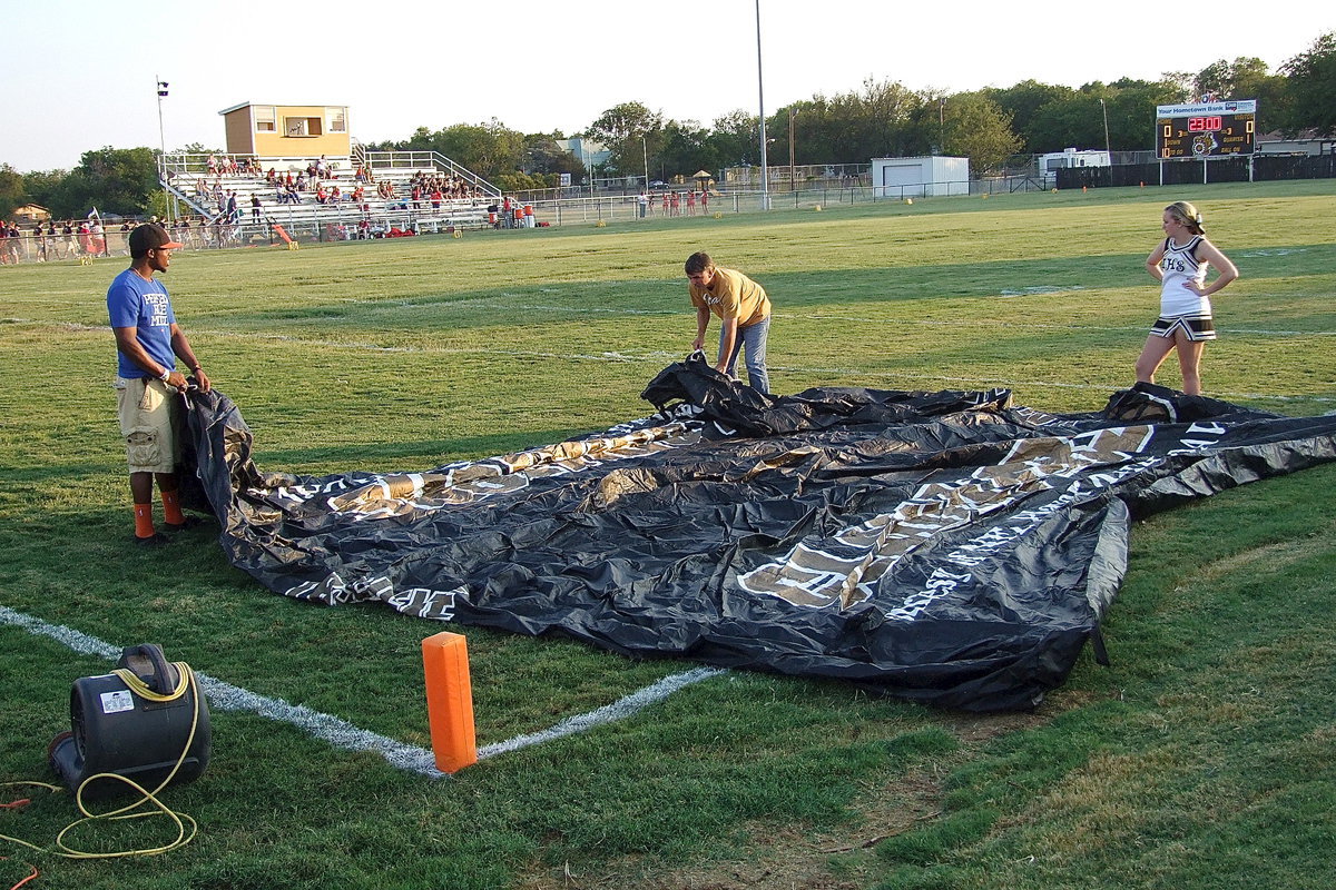 Image: Italy HS Cheerleader Kelsey Nelson comes over to supervise Jasenio Anderson and Gary Wood on how to assemble the air tunnel.