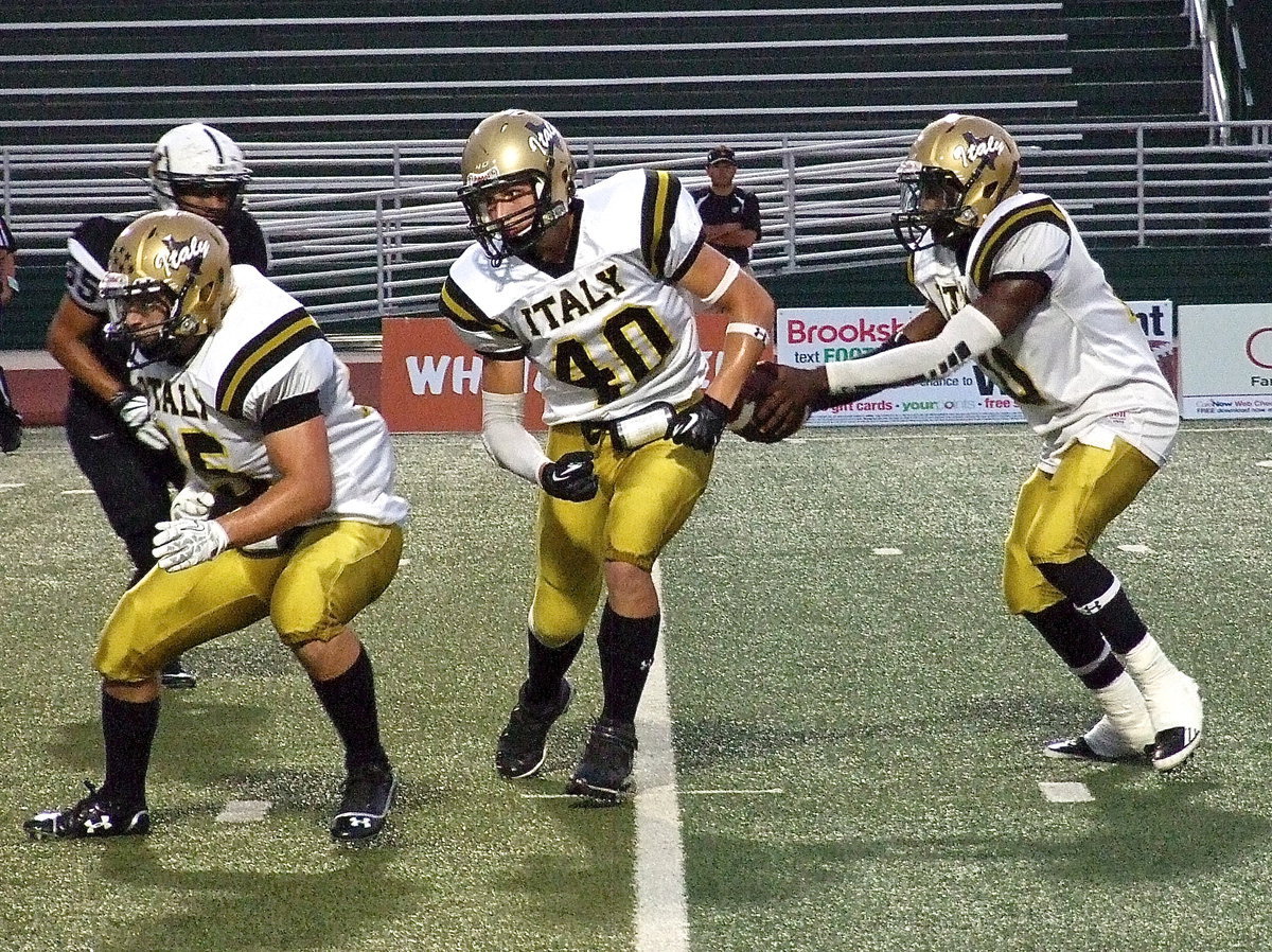 Image: Italy’s Shad Newman(25) leads as quarterback TaMarcus Sheppard(10) fakes a handoff to Coby Bland(40).