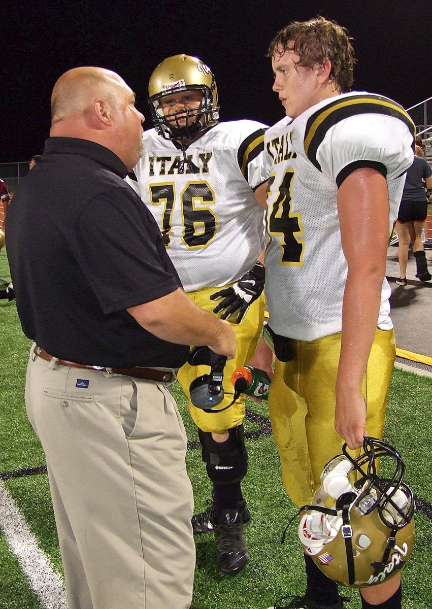 Image: Coach Wayne Rowe talks trench warfare with defensive linemen Colin Newman(76) and Bailey Walton(54).