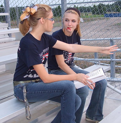 Image: Color Guard captain Anna Riddle discusses the halftime routine with fellow flag waver Paige Cunningham.