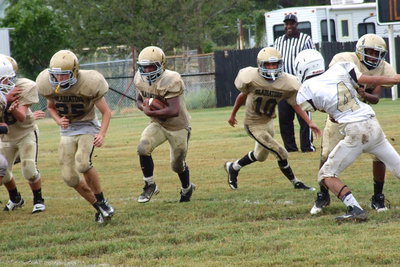 Image: Kyle Tindol(25) and Anthony Lusk(72) open a running lane for Kendrick Norwwod(20) after quarterback Tylan Wallace(10) hands Norwood the ball.