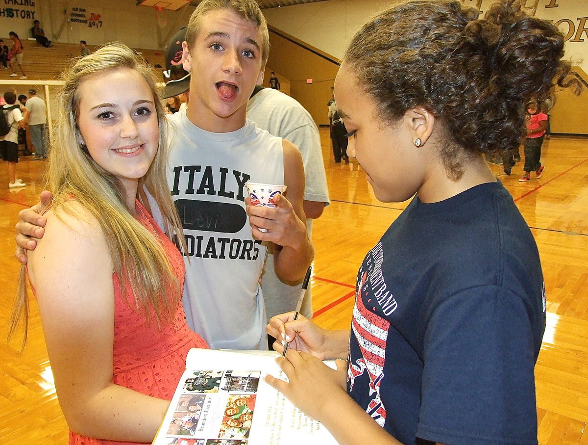 Image: Levi McBride gets brain freeze from his snow cone as Vanessa Cantu signs Kelsey Nelson’s yearbook.