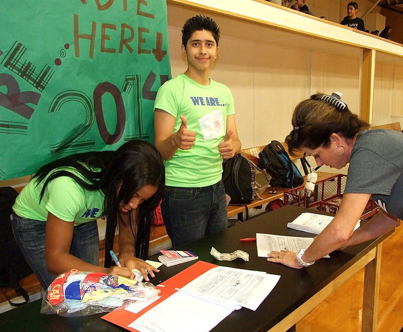 Image: Joseph Sage gives two thumbs up as fellow yearbook staffer Bernice Hailey helps Andi Windham order a 2013-2014 yearbook.