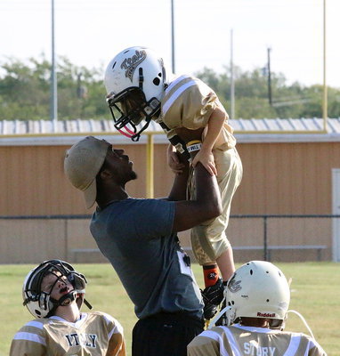 Image: C-team head coach Jasenio Anderson has his Lil’ Gladiators feeling 10 feet tall and bulletproof as he lifts Dylan Rose(6) toward the football Gods.