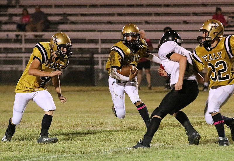 Image: Joe Celis(2) looks for room to run behind blockers Justin Wood(4) and Eli Garcia(32).