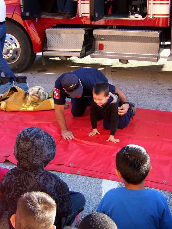 Image: Tommy and Fireman Cate are practicing the stop, drop and roll procedure when there is a fire.