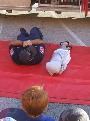 Image: Fireman Cate and Stafford student Charlie are demonstrating the roll in stop, drop and roll.