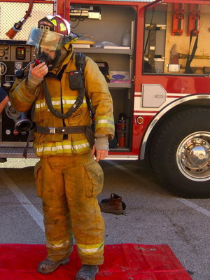 Image: Fireman Brad Chambers suited up in his fireman gear and is showing the students how he breathes during a fire.