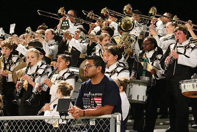 Image: Band director Jesus Perez watches the action on the field as his band members entertain the fans.