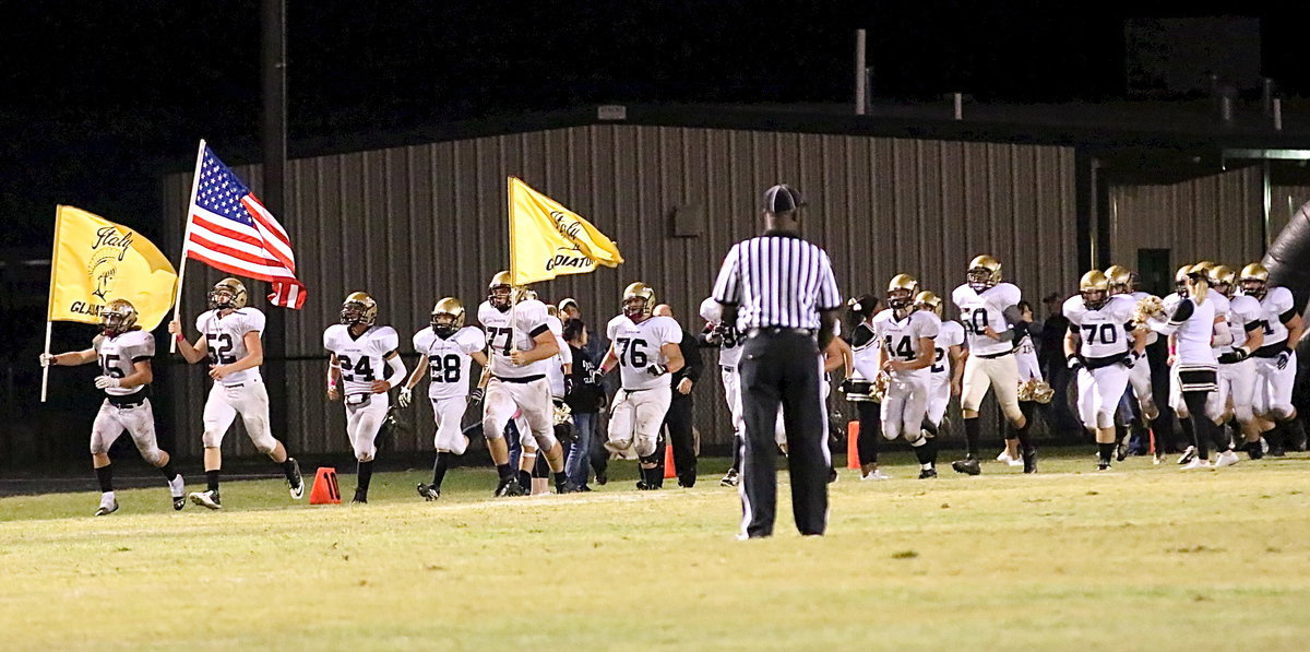 Image: The Gladiators take the field for the second-half with seniors Shad Newman(25), Bailey Walton(52) and Kevin Roldan(77) handling the flag duties.