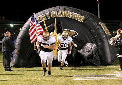 Image: Two of Italy’s 12 seniors in Kevin Roldan(77) and Zain Byers(50) lead the Gladiators onto the field and into a district battle with Crossroads.