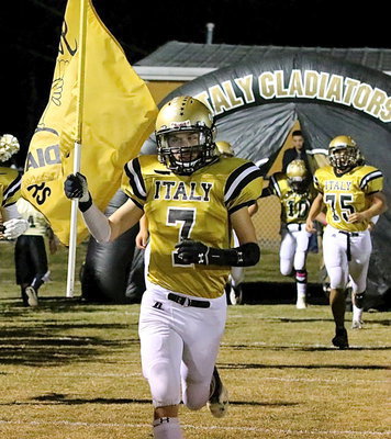 Image: Sophomore Ryan Connor(7) carries the flag as the Gladiators take the field.