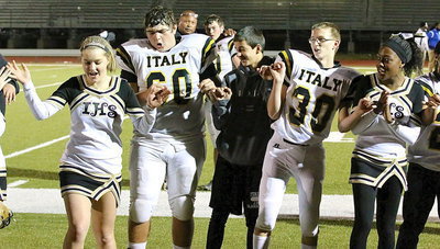 Image: Singing the school song loud and proud are cheer captain Taylor Turner, Kevin Roldan(65), water boy Gary Escamilla, Hunter Ballard(30) and cheerleader K’Breona Davis as Coach Mayberry gives, “Zilla,” a hug in the background.