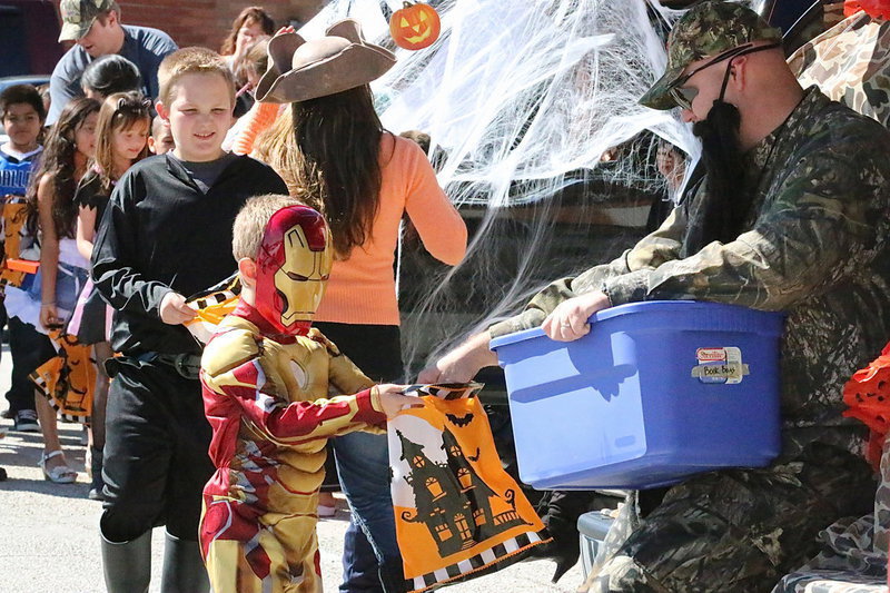 Image: Iron Man collects candy from a parent dressed as a Duck Dynasty character.