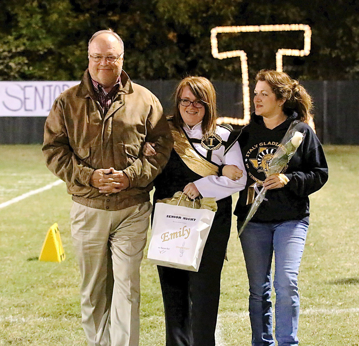 Image: Gladiator Regiment Band senior assistant drum major Emily Stiles is escorted by her parents Mark Stiles and Clover Stiles.