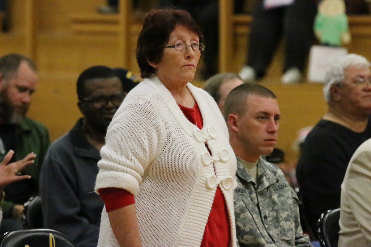 Image: Veteran Karen Mathiowetz rises during the playing of service songs by the Gladiator Regiment Band.