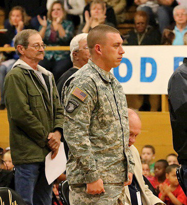 Image: Current Air Force soldier David Clingan rises during the playing of service songs by the Gladiator Regiment Band.