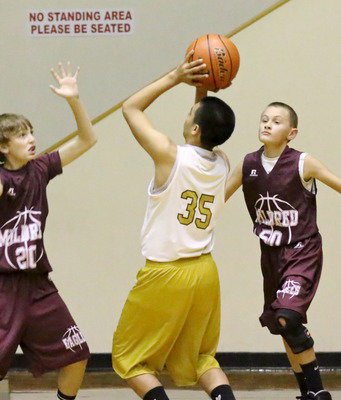Image: Jonathan Salas(35) rises for a shot over two Mildred defenders during the junior high 7A game.
