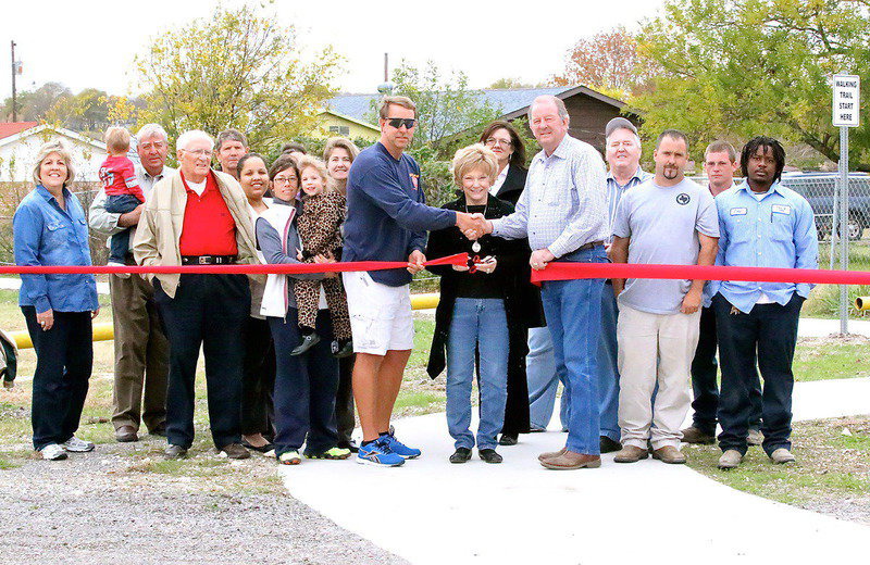 Image: IYAA president/Italy EDC Board member Charles Hyles, Mayor James Hobbs and his wife Joyce, along with former and current city employees and citizens of Italy, help dedicate the new concrete walking trail installed around Upchurch Park in Italy.