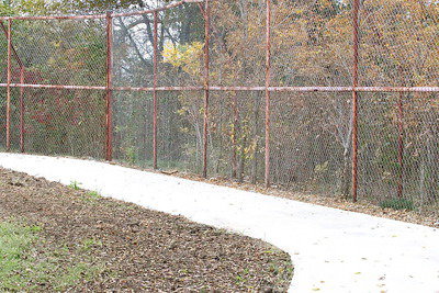 Image: The walking trail follows the inside of a baseball field’s outfield fence. Charles Hyles is hoping to install a second fence to better separate the trail from any games being played game.