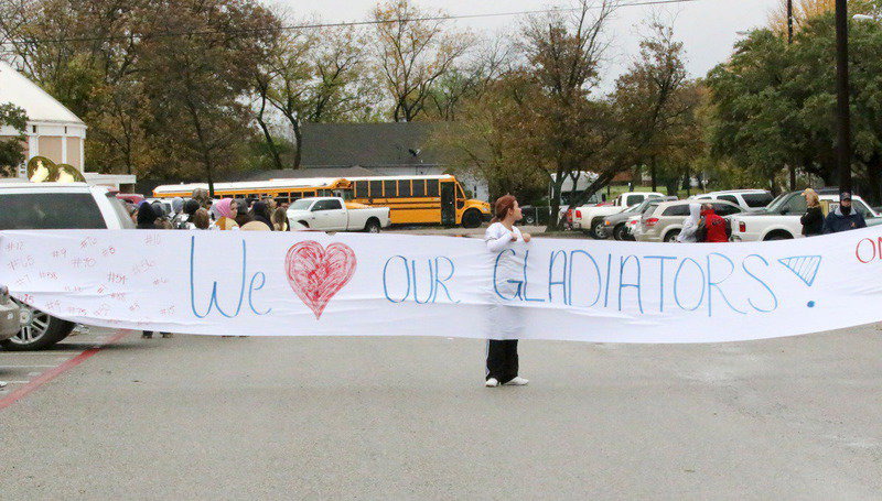Image: Italy High School cheerleader Kristian Weeks helps hold up a banner as the team bus approaches during a heroes sendoff from the school’s campus Friday before the game between the Gladiators and Collinsville for the area championship.