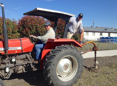 Image: Former City of Italy council member, Jimmy Hyles, steers the tractor while his son, Charles Hyles, helps the hole digger punch the thru the stubborn terrain.