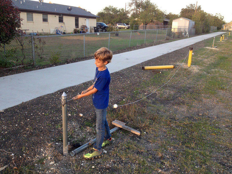 Image: Case Hyles slides a cable thru posts to help keep the parking lot separate from the walking trail.