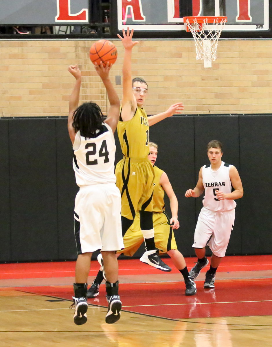 Image: Ryan Connor(1) challenges a Zebra jump shooter late in the game.