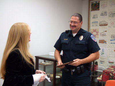 Image: Jeannie Richardson presents Police Chief Phoenix with his plaque with a smile.