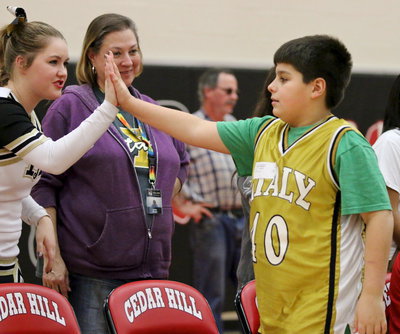 Image: Care professional at Stafford Elementary, Lynn Rudd looks on proudly as Mikey South(40) receives a high-five from cheerleader Taylor Turner after South scored a basket.