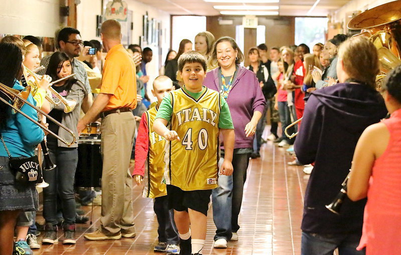 Image: Special olympians Mikey South(40) and Charlie Bolin(5), along with CBI teacher Lynn Rudd, lead Team Italy down the hallways while being cheered on by fellow students as the band played a beat for our champions!
