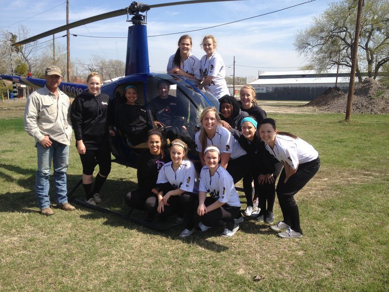 Image: During a lunch break between softball games, the Lady Gladiators watch in awe as a helicopter cowboy lands in the lot next to their picnic lunch.
