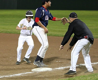 Image: First base coach Jackie Cate helps Hunter Ballard(1) re-locate the bag with a very large obstacle in the way.