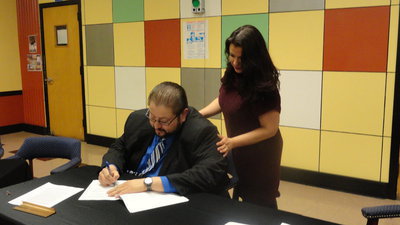 Image: Lisa Velasco watches as her husband, Jaime, signs the contract to be the new superintendent at the Italy ISD.