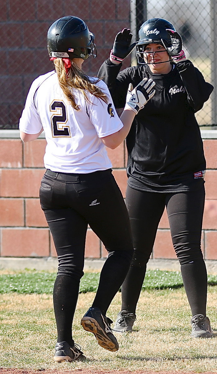 Image: Jaclynn Lewis crosses home plate and then congratulates teammate Madison Washington(2) after Washington completes her homerun lap around the diamond.