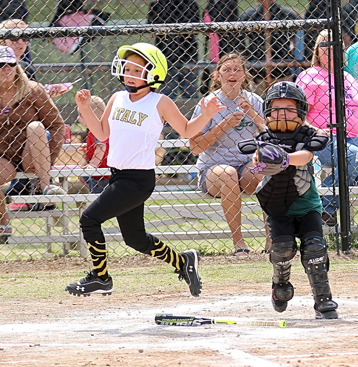 Image: Ella Hudson avoids the tag at the plate to score a run.