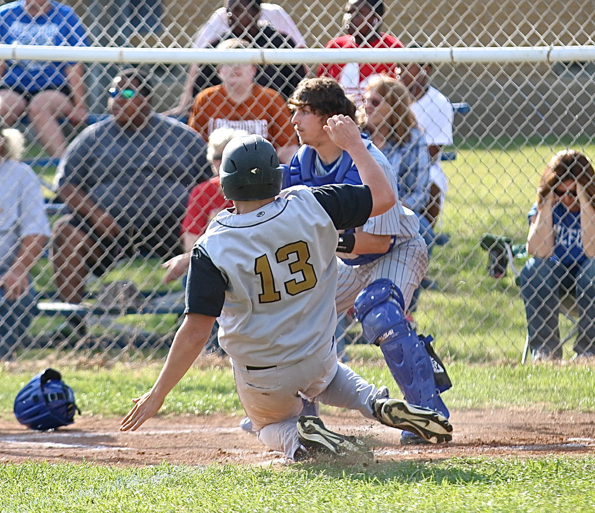 Image: Senior Gladiator Bailey Walton(13) launches into a slide with catcher Bryan Fedrick defensing for Milford. Walton would be ruled safe and both players came out of the play unscathed.