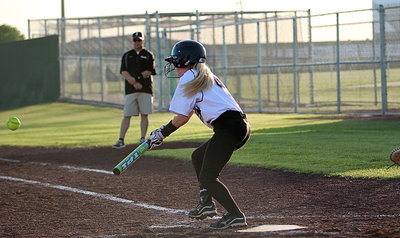 Image: Britney Chambers(4) connects on the ball as her father and first-base coach Michael Chambers looks on.