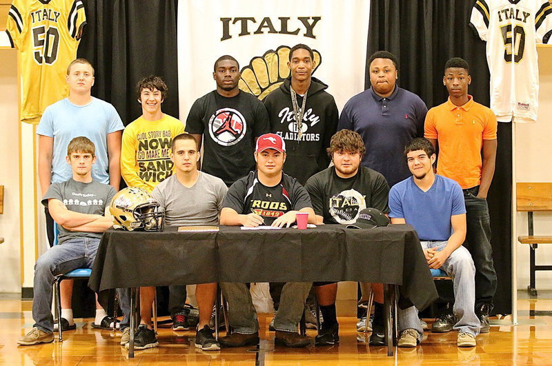 Image: Zain Byers is joined by many of his fellow seniors while he signs his letter of commitment to play football for the Austin College Kangaroos. Back row (L-R): Bailey Walton, Andrew McCasland, TaMarcus Sheppard, Trevon Robertson, Darol Mayberry and Eric Carson. Front row (L-R): Justin Wood, Cody Medrano, Zain Byers, Kevin Roldan and Tyler Anderson.