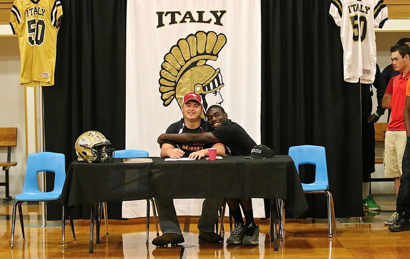 Image: Zain Byers is feeling the love after signing his letter of commitment inside George E. Scott Coliseum on the Italy High School campus. Providing the hug is senior teammate TaMarcus Sheppard.