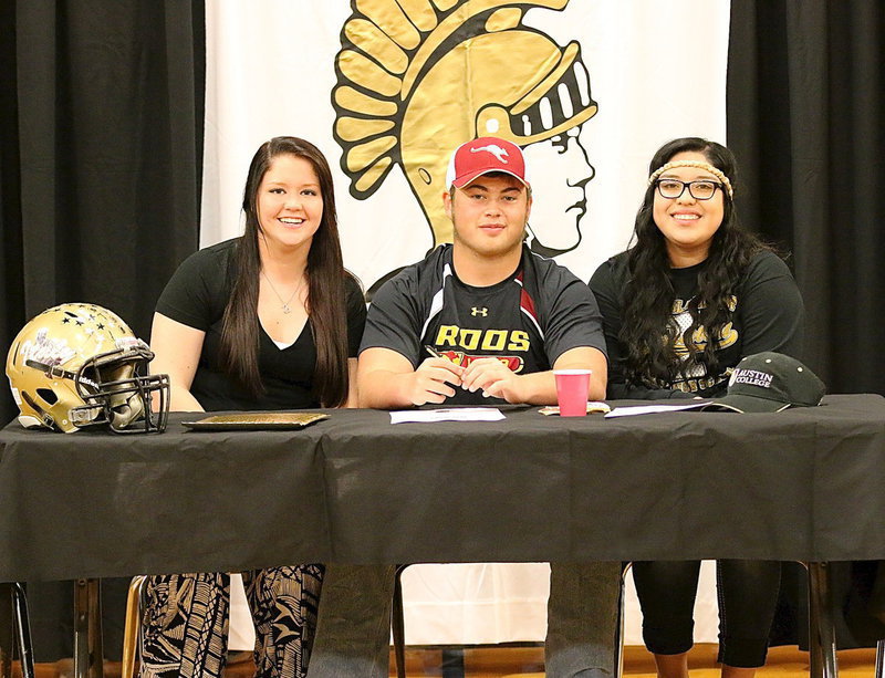 Image: Lady Gladiators Paige Westbrook and Monserrat Figueroa pose with fellow senior Zain Byers after he signed his commitment letter to Austin College.